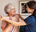 Nurse helping older woman stretch her arm across her chest
