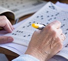 Close-up of woman's hands holding a pen and filling out a crossword puzzle