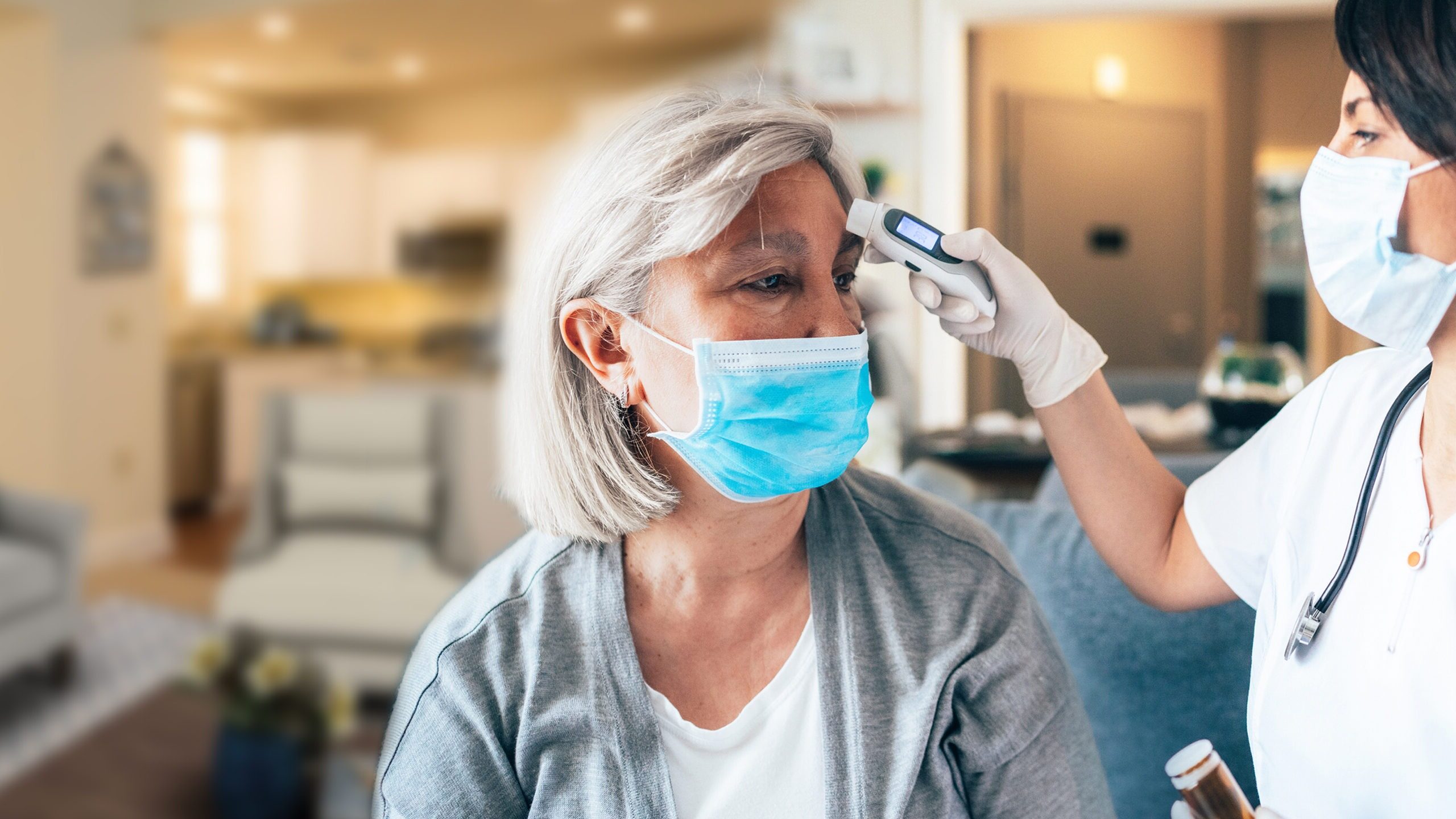 Nurse wearing mask using forehead thermometer to check patients temperature